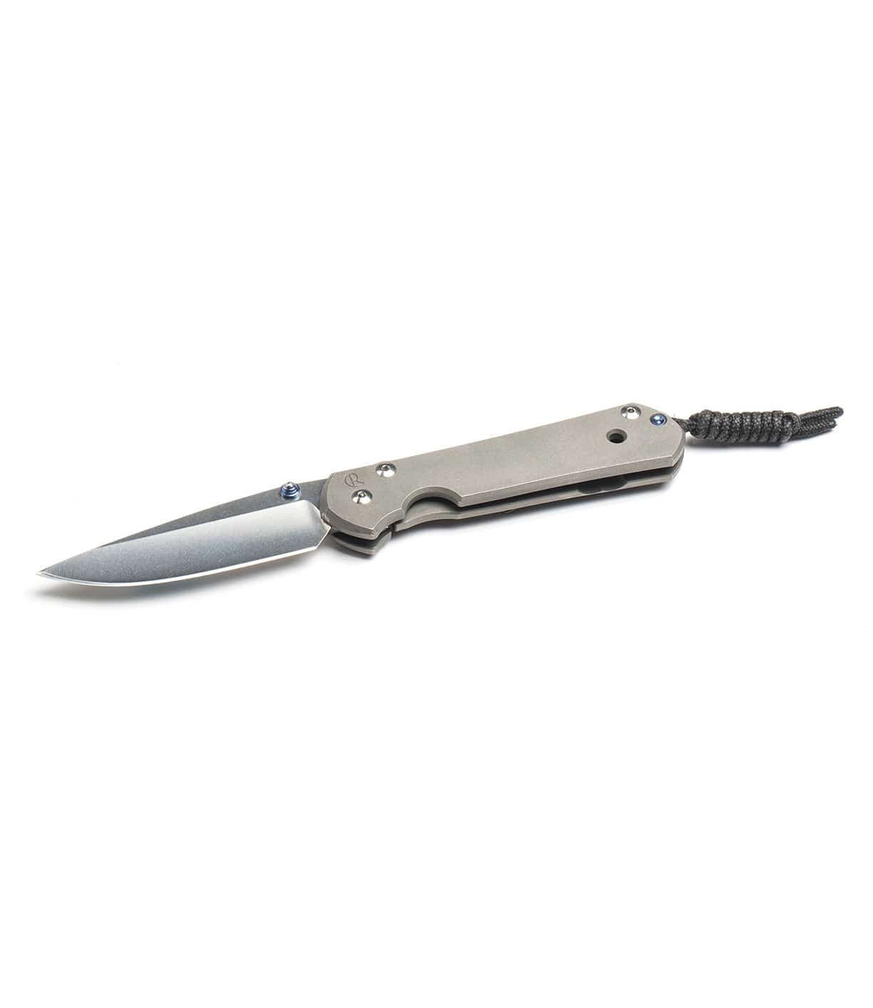 A folding knife with a metallic handle, a sharp blade, and a lanyard attached to the end rests on a white background.