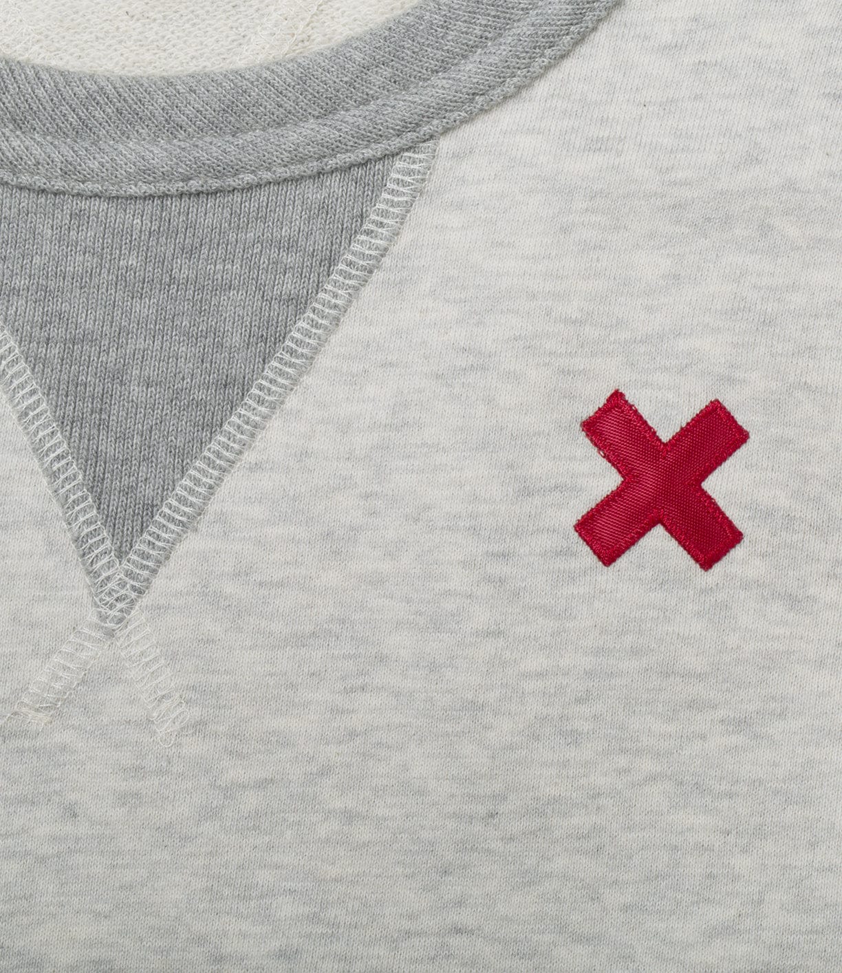 Close-up view of a grey and white garment with a red stitched X symbol near the neckline.