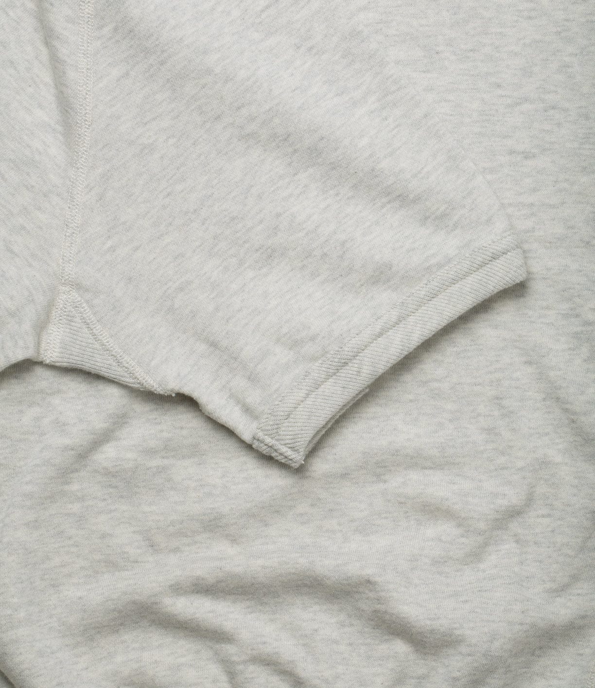 A close-up view of a light gray T-shirt's sleeve and part of the torso area, showing the seam and fabric texture.