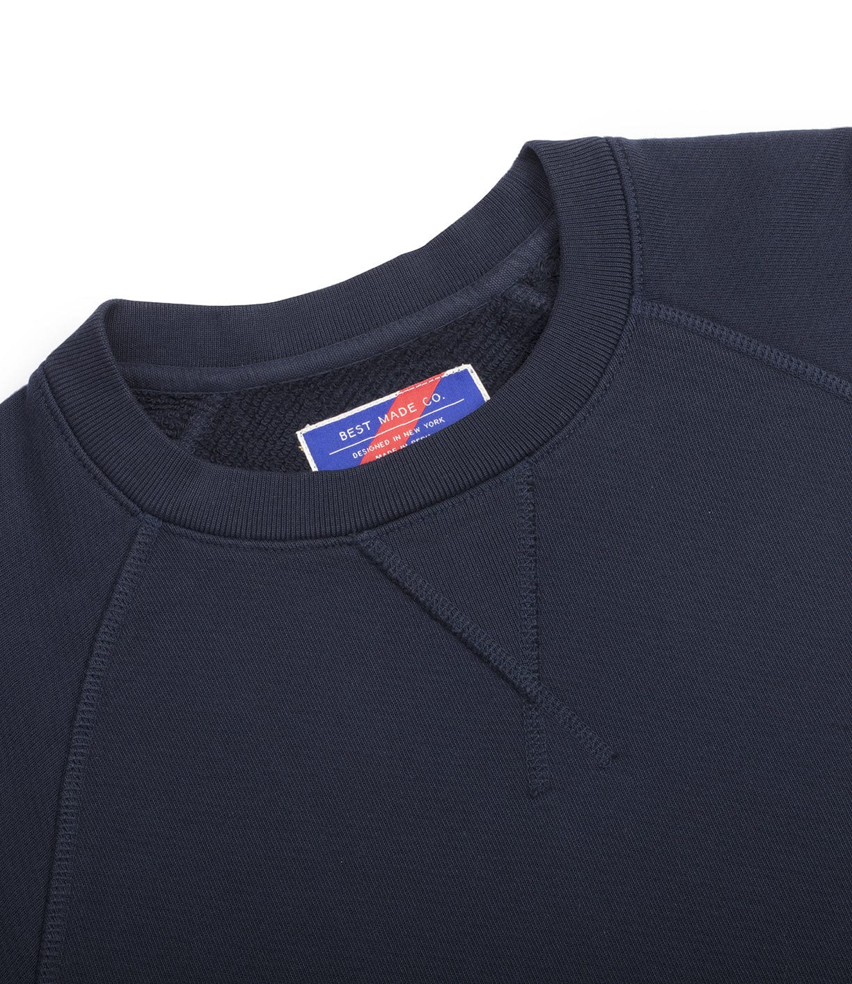 Close-up of a black crewneck sweatshirt with a blue, red, and white label on the inside collar reading Best Made Co.