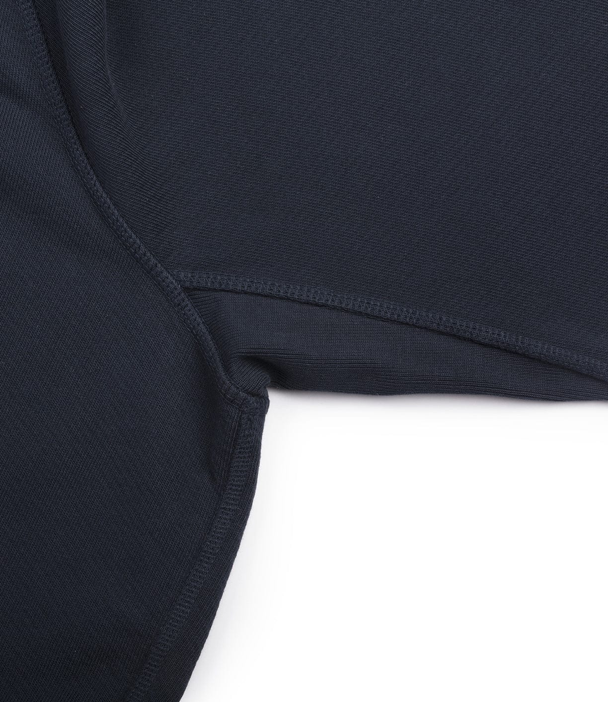 Close-up of a dark fabric seam with visible stitching on a white background. The fabric appears to be part of an article of clothing.