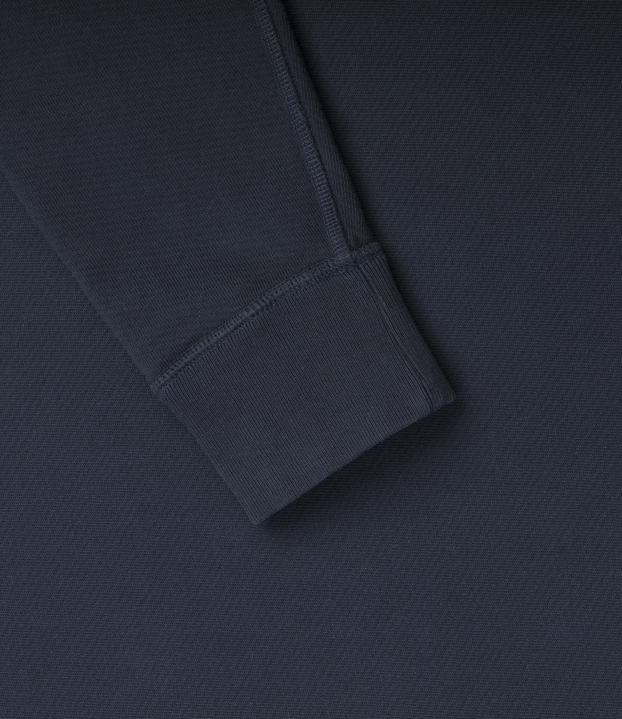 Close-up of the cuff of a long-sleeve dark gray garment, displaying the texture and stitching details.