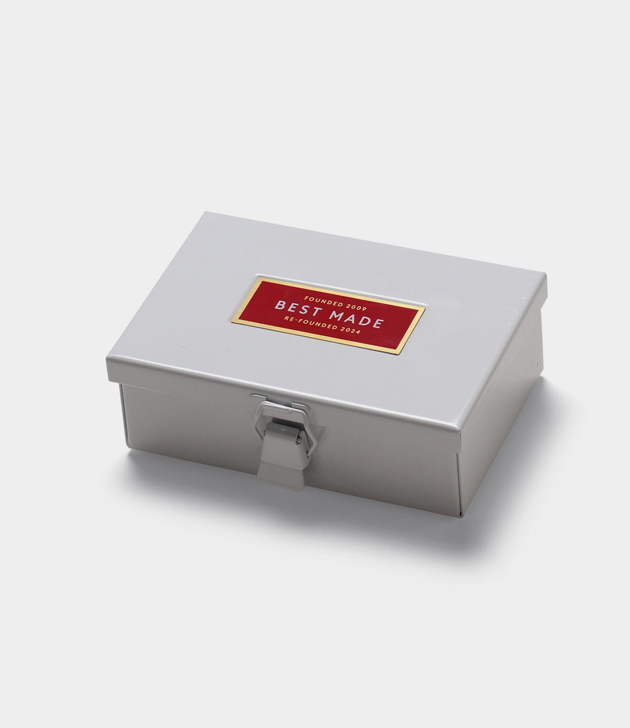 A closed, rectangular metal box with a latch and a red and gold label that reads Best Made on the lid.