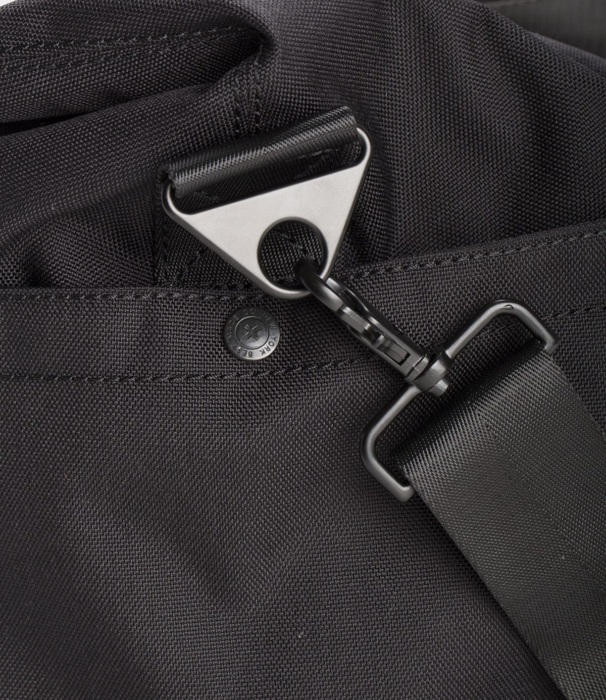 Close-up of a black strap attached to a D-ring carabiner on a black fabric bag.