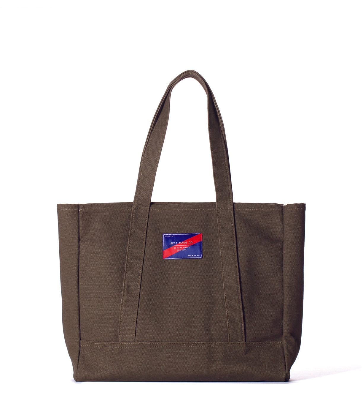 A brown canvas tote bag with two handles and a small blue and red rectangular patch on the front.