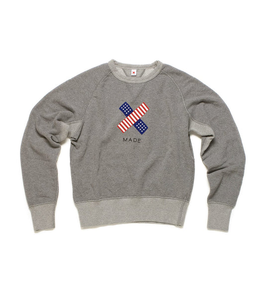 A grey sweatshirt with long sleeves features a graphic of a bandage with an American flag design and the word MADE printed below.