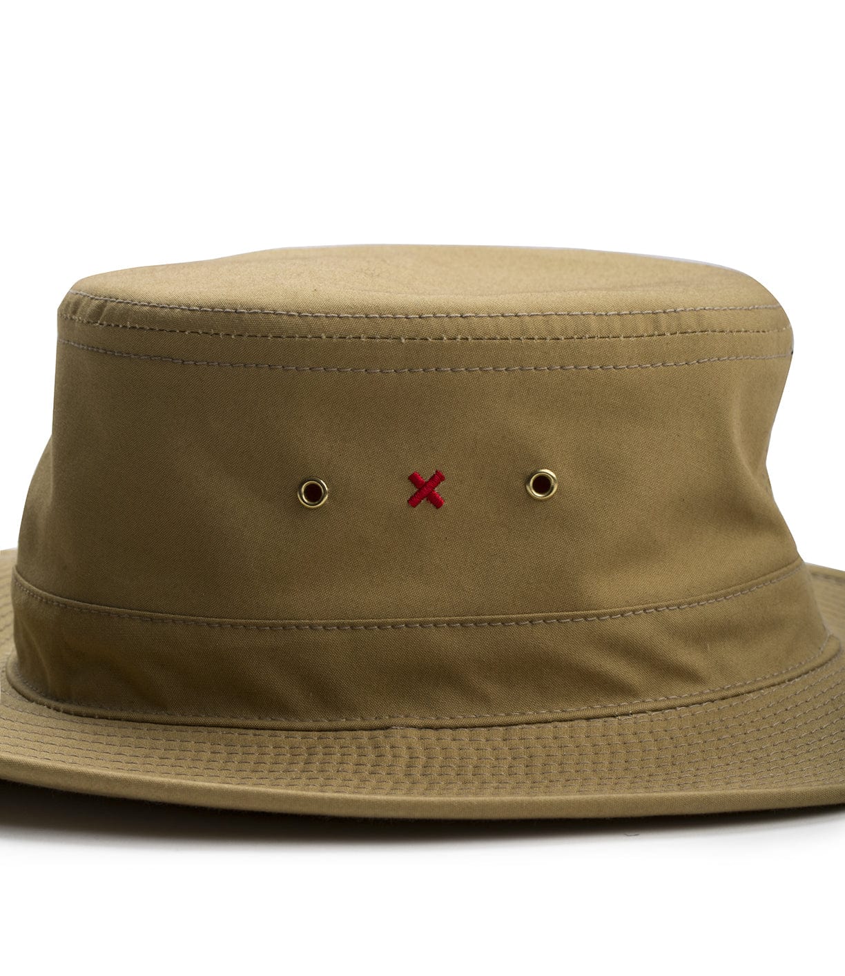 A khaki-colored bucket hat featuring two metal ventilation grommets and a small red X on the front.