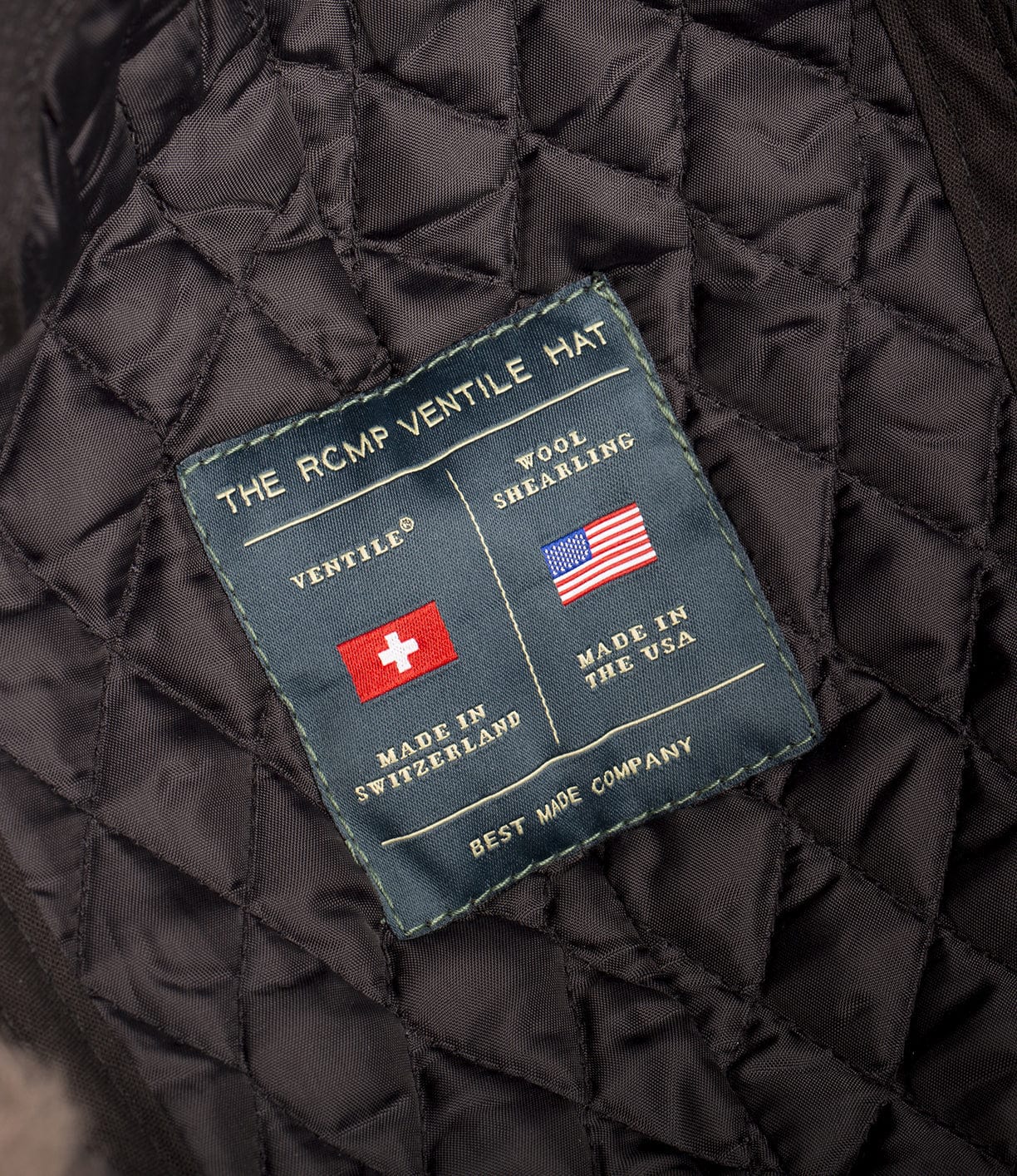 Close-up of a quilted textile label with details about The RCMP Ventile Hat, noting Made in Switzerland for ventile and Made in the USA for wool shealing. Label by Best Made Company.