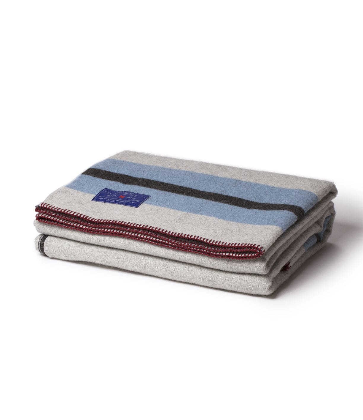 A folded gray blanket with blue and black stripes, featuring a red trim and a blue label in the center.