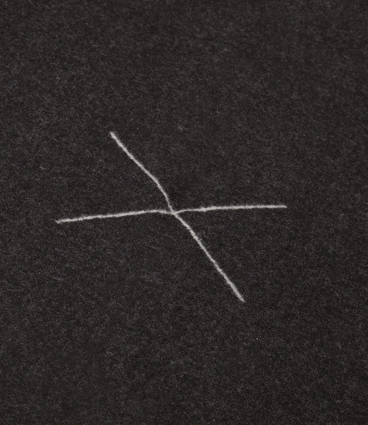 An abstract white cross-like mark is on a dark surface.