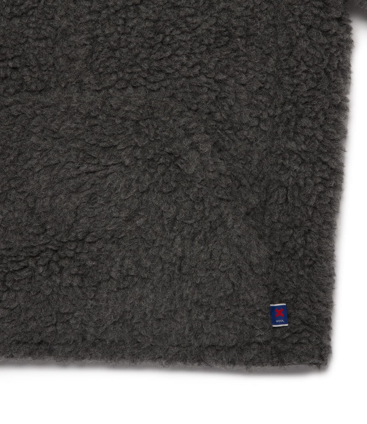 Close-up of dark gray, textured woolen fabric with a small tag featuring a red and blue logo in the lower right corner.