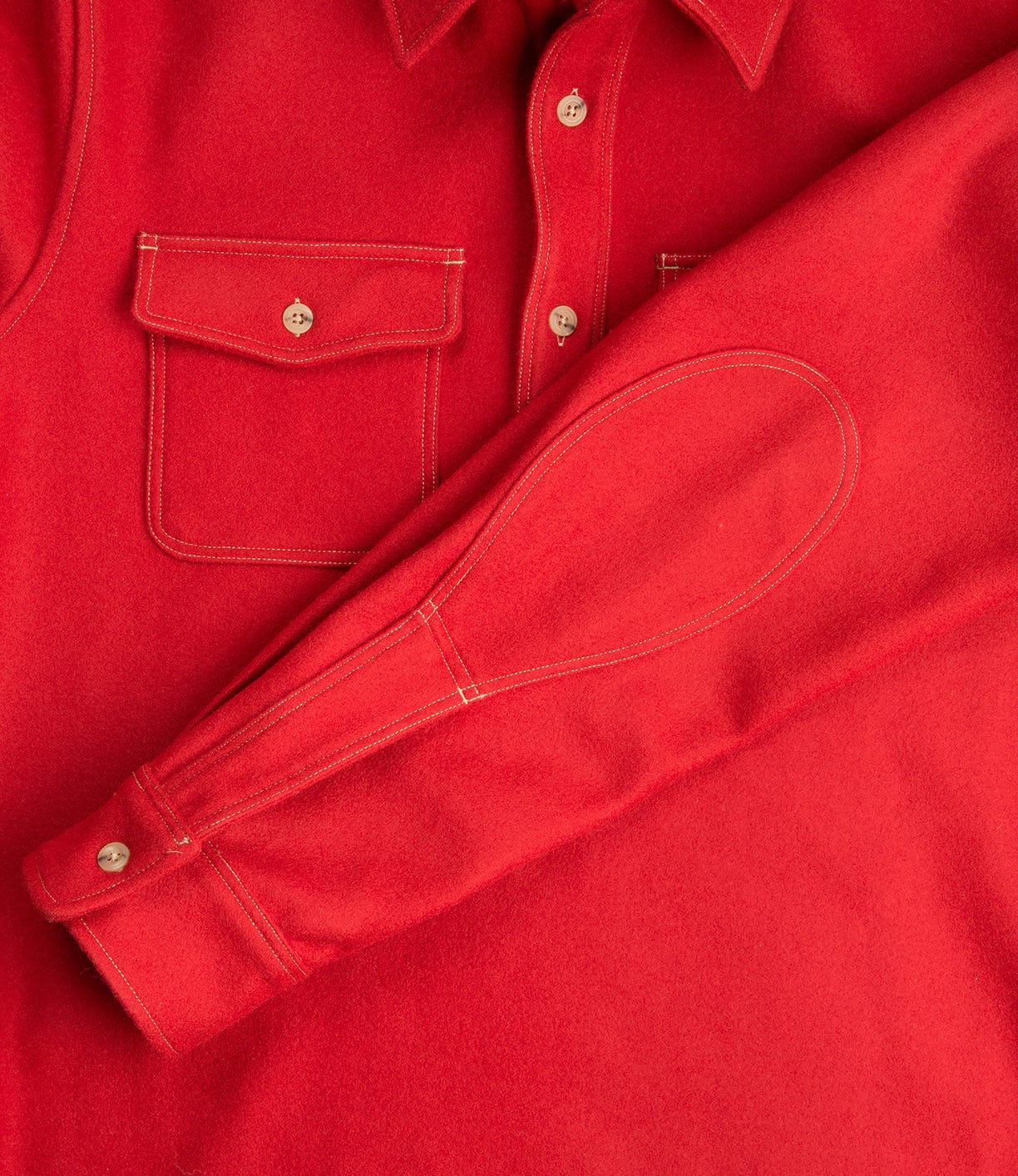 Close-up of a red button-up shirt with a chest pocket and white stitching, showcasing the collar and a folded sleeve.