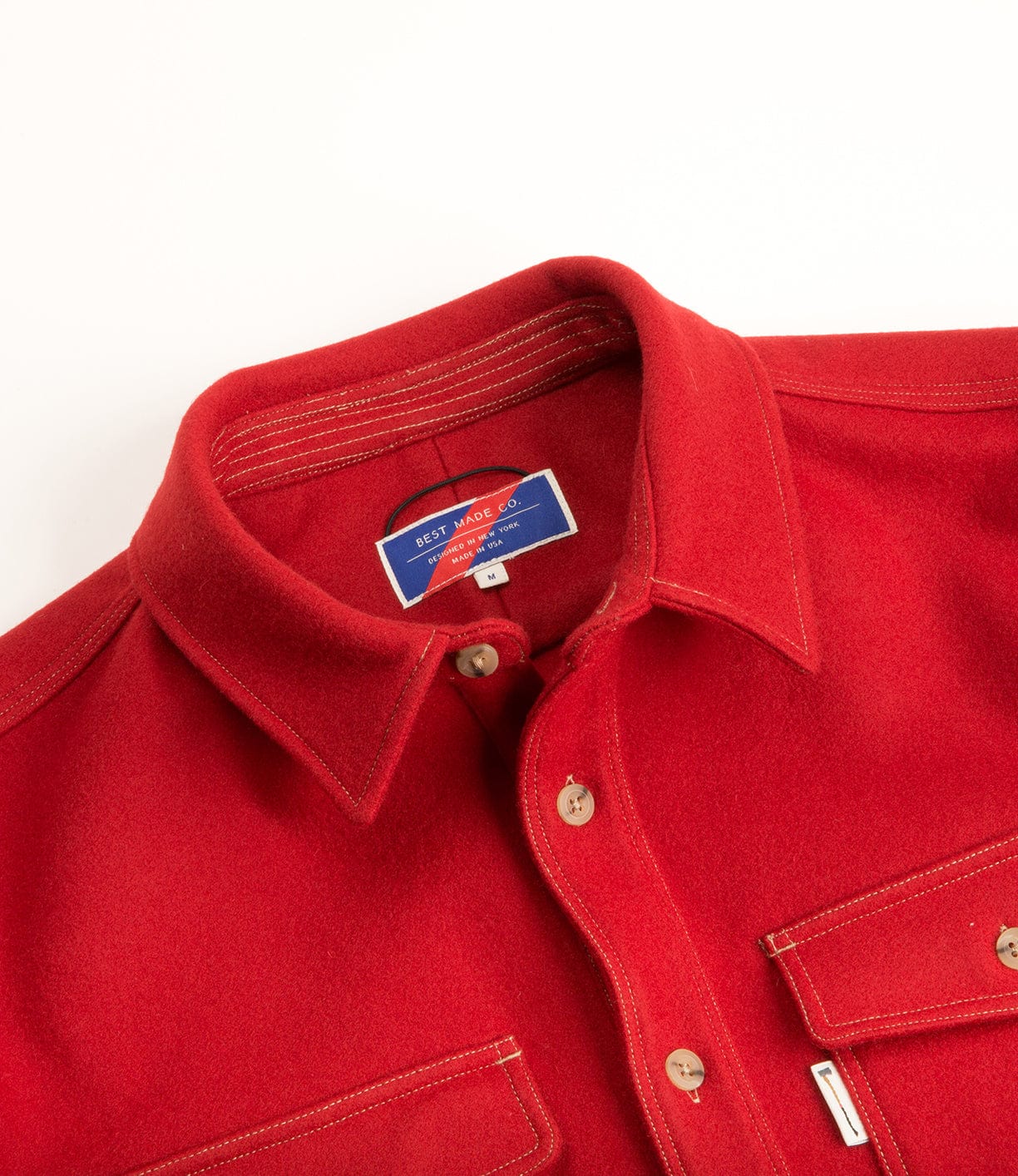 Close-up of a red button-up shirt with two chest pockets and a blue label on the inner collar.